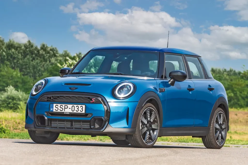 Színes betétes hűtőmaszkjáról ismerhető fel a 2022-es modell a  Mini Cooper S aut.  A LED-es fényszórók lehetnek adaptívak, az új 18 colos alufelni mintázata álló helyzetben is forgást imitál